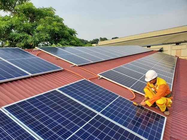 Man in hardhat installing a solar panel to a roof