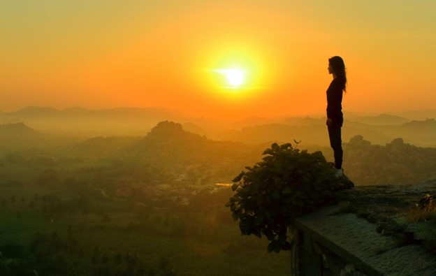 Woman standing on a hill looking at the sun