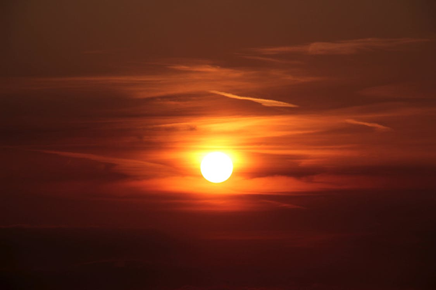 Sun showing orange in a cloudy sky