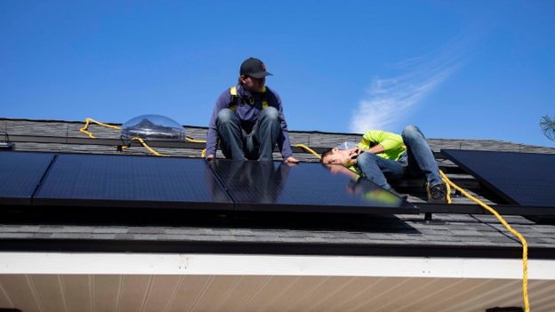 Two men installing a solar panel on a roof