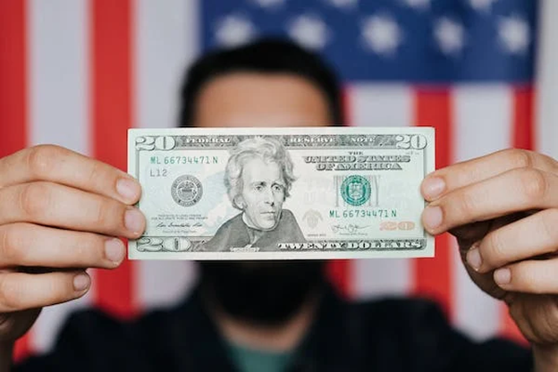 Man holding $20 bill with the American flag in the background